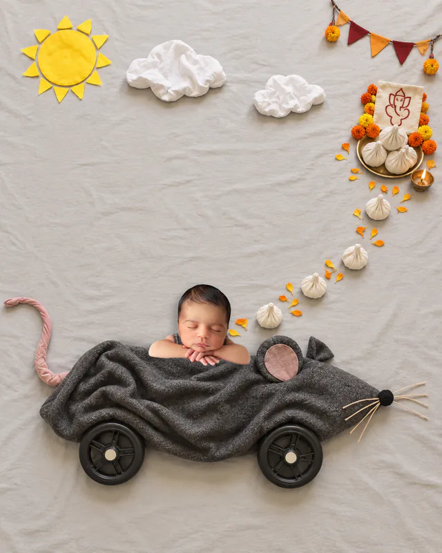 Sleeping baby in a felt mouse-shaped car with a trail of modaks leading to a Ganesha puja plate